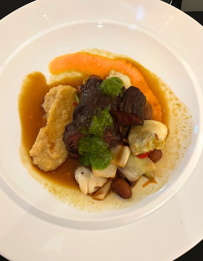 Beef tenderloin atop a colourful plate of vegetables