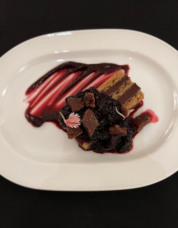 Chocolate dessert - cake with raspberry coulis and decorative flowers