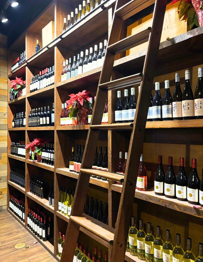 A wall of wine with a ladder to reach the higher bottles