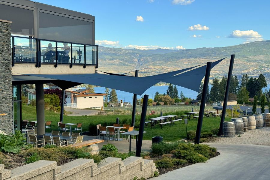 View of a restaurant overlooking vineyards and lake. There is an upstairs and downstairs patio. 