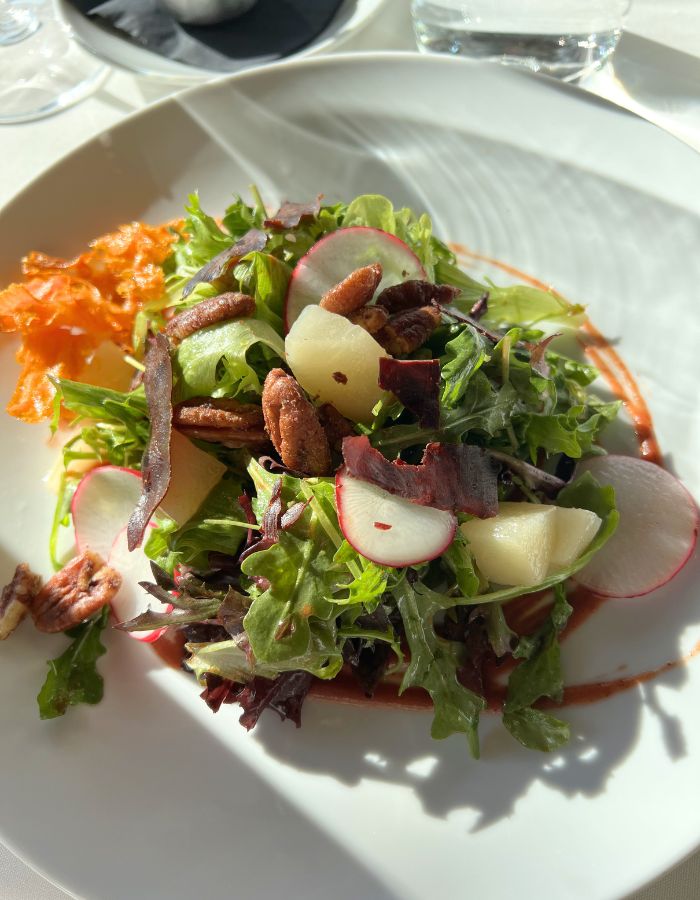 Salad on a white plate - greens, radishes, pecans and carrot